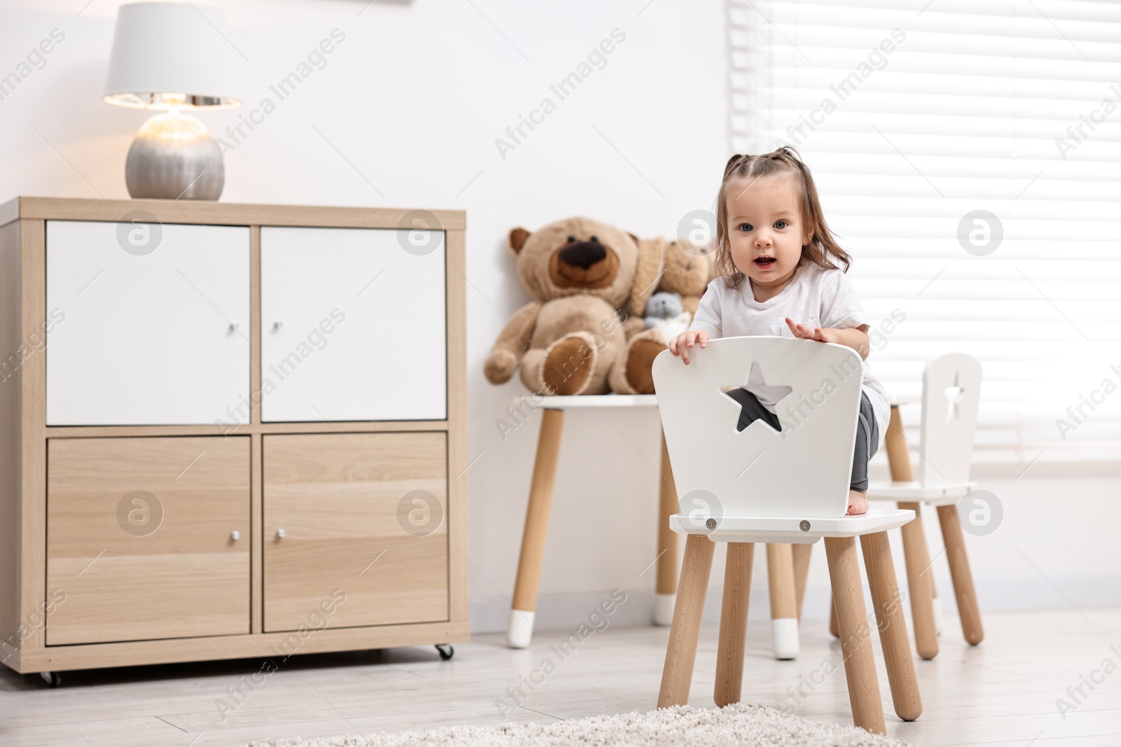 Photo of First steps. Cute little baby on small chair at home