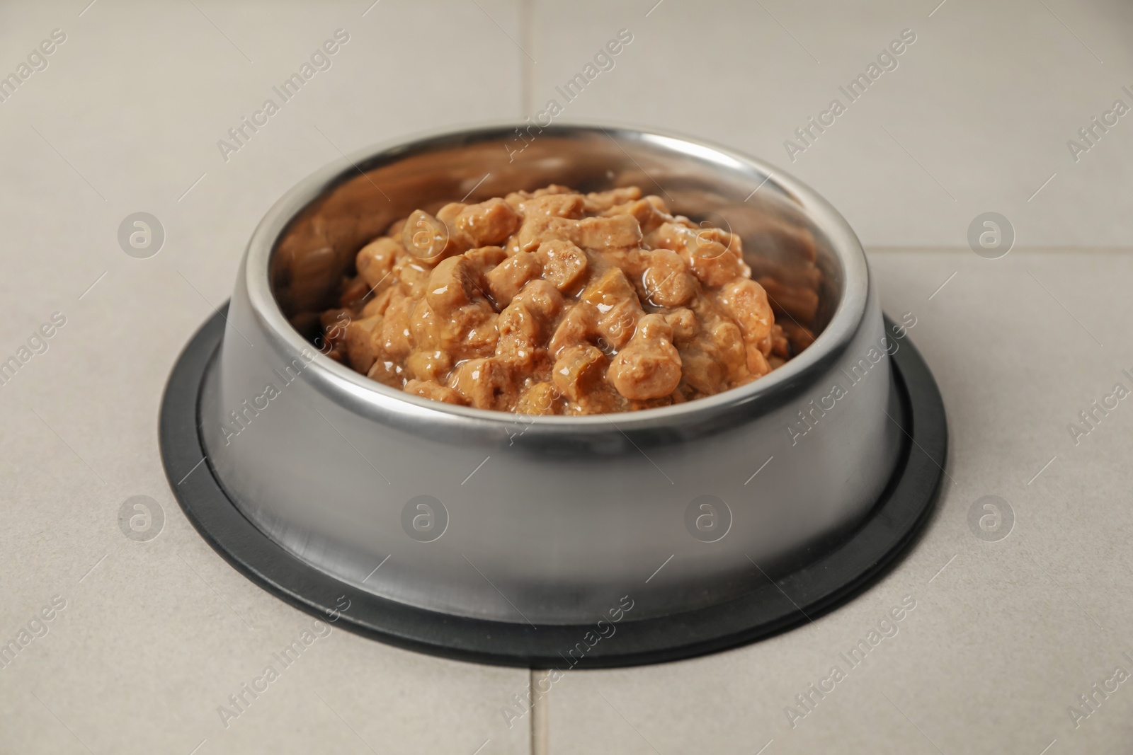 Photo of Wet pet food in feeding bowl on floor