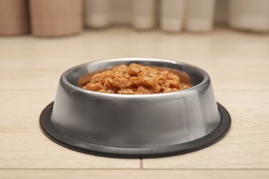 Photo of Wet pet food in feeding bowl on floor indoors