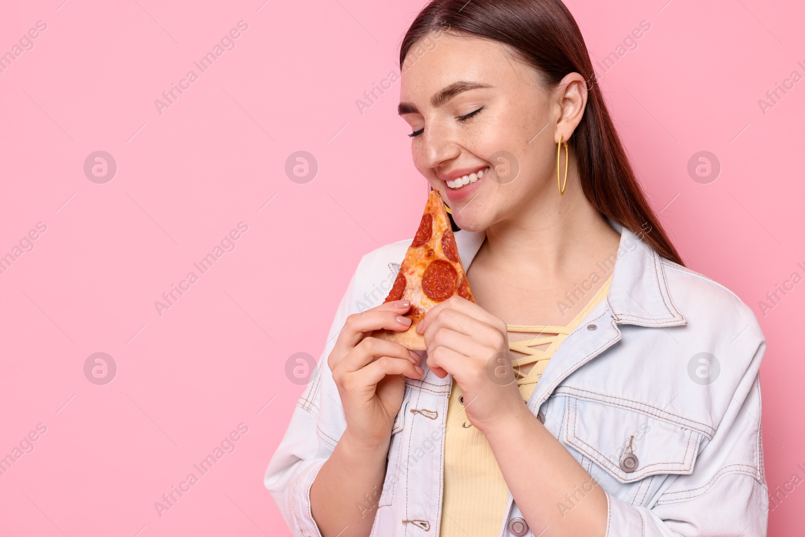 Photo of Beautiful woman with delicious pizza on pink background, space for text