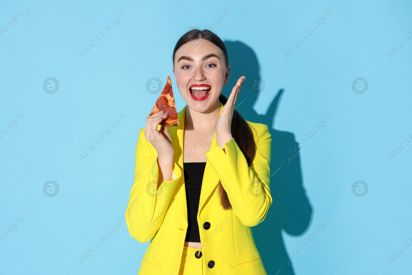 Photo of Emotional woman with piece of pizza on light blue background