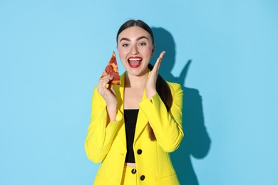 Emotional woman with piece of pizza on light blue background