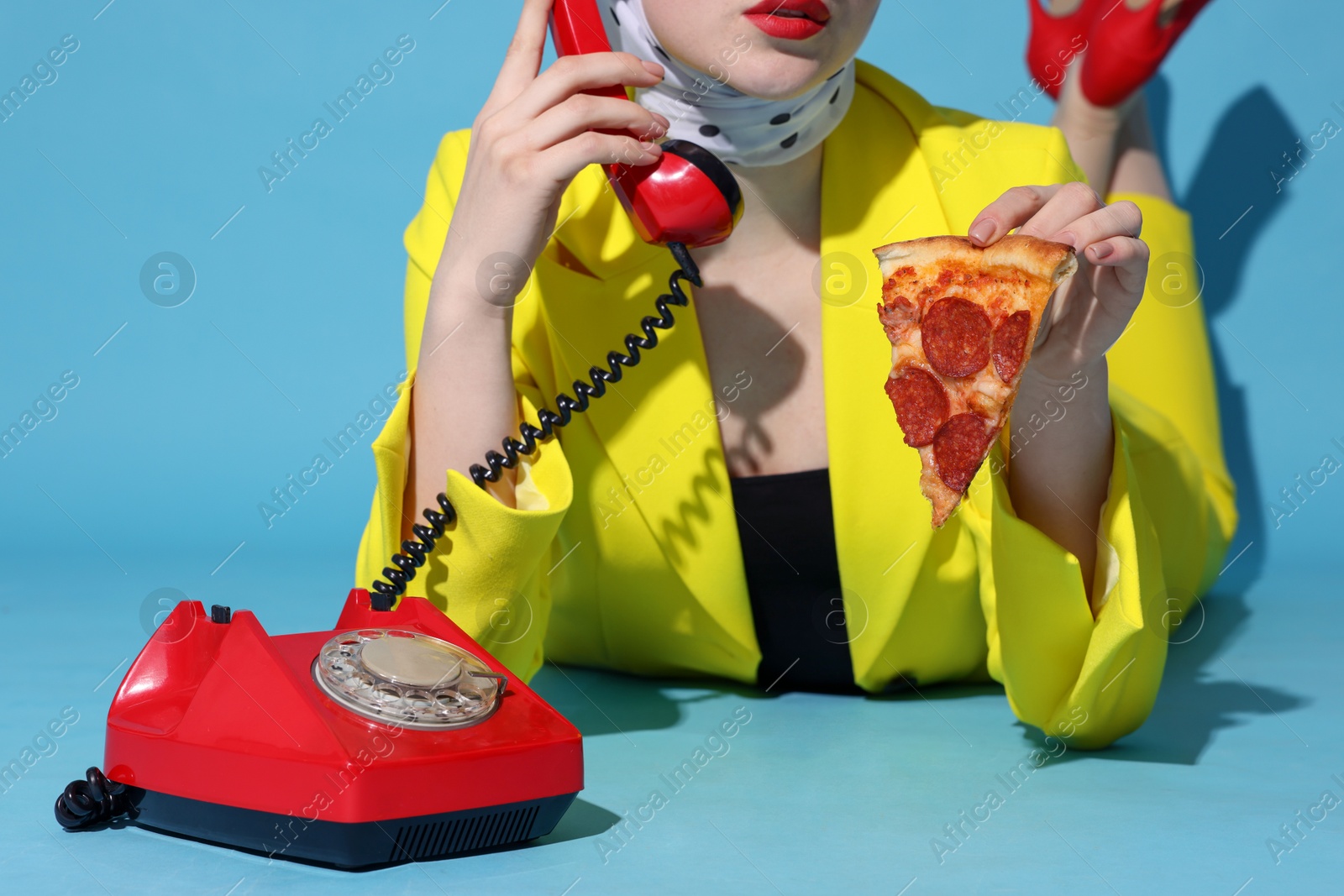 Photo of Woman with delicious pizza and telephone on light blue background, closeup