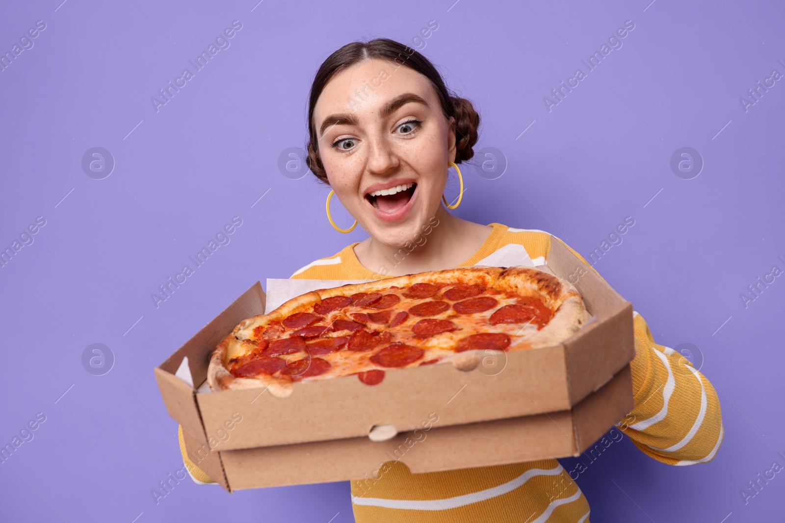 Photo of Surprised woman with delicious pizza on violet background