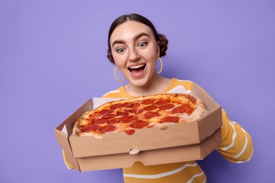 Photo of Surprised woman with delicious pizza on violet background