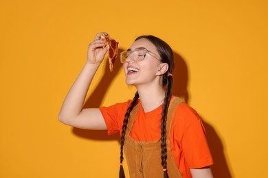 Photo of Beautiful woman with piece of delicious pizza on orange background