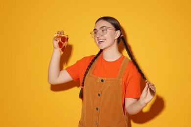 Photo of Beautiful woman with piece of delicious pizza on orange background