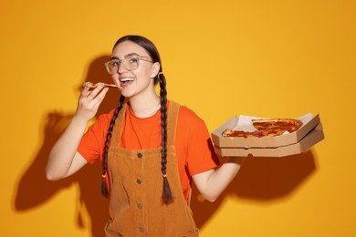 Photo of Beautiful woman with delicious pizza on orange background