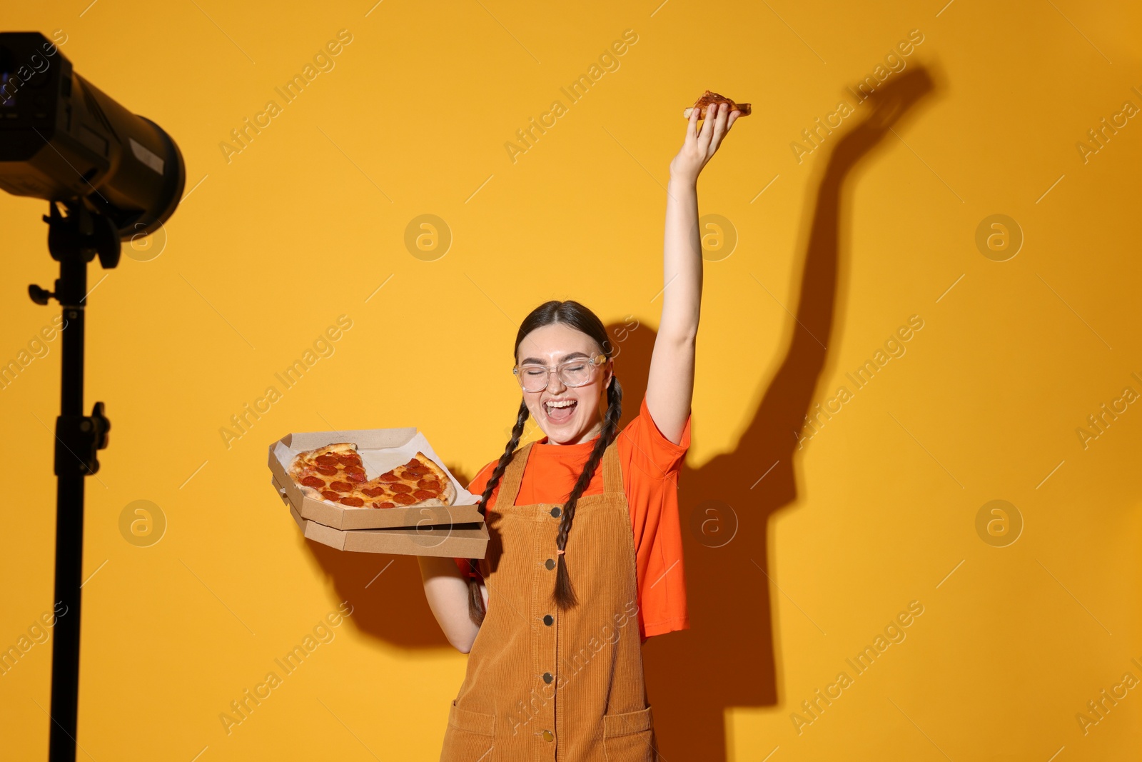 Photo of Emotional woman with delicious pizza against orange background