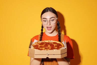 Photo of Surprised woman with delicious pizza on orange background