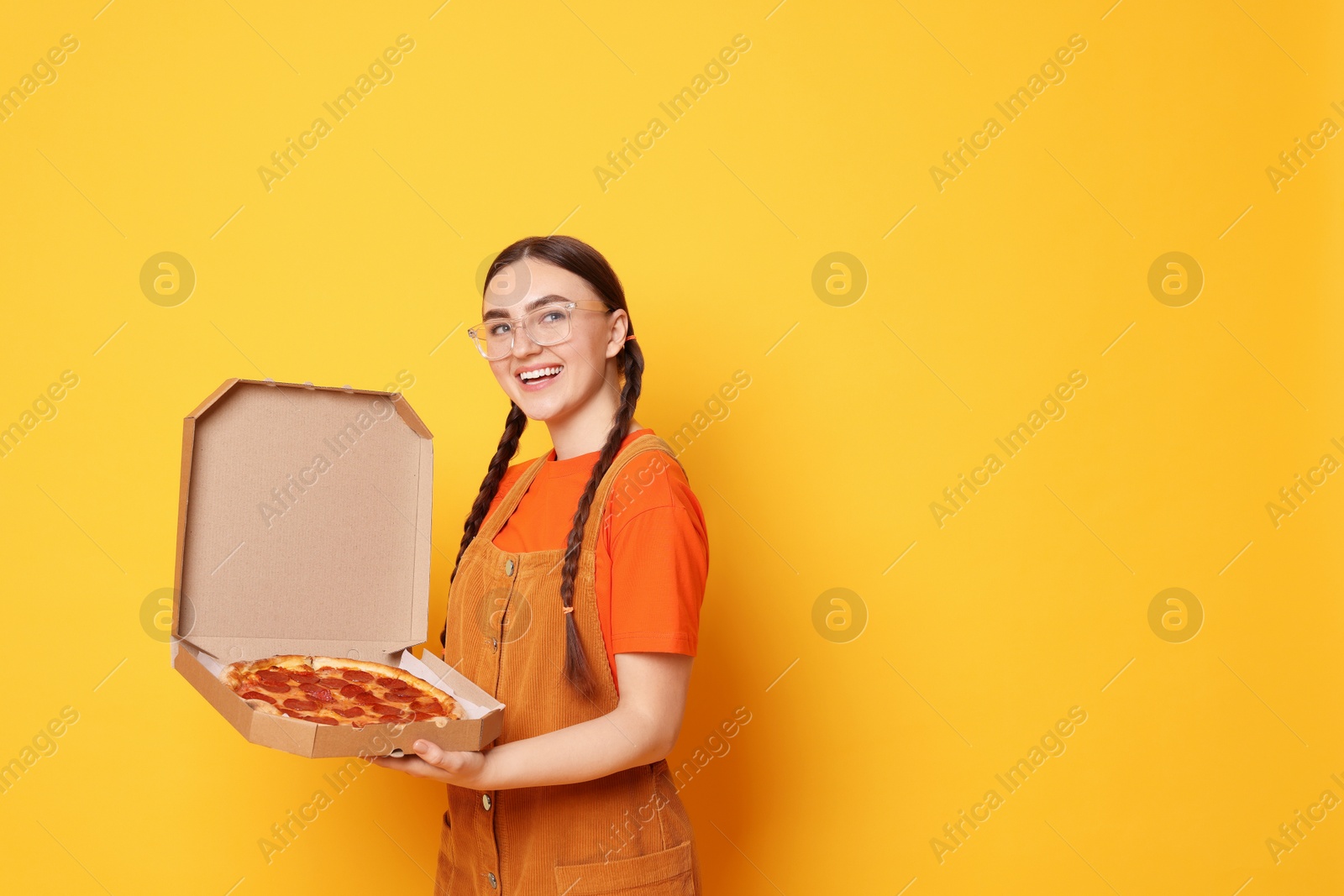 Photo of Beautiful woman with delicious pizza on orange background, space for text