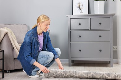 Photo of Happy decorator rolling out carpet in room