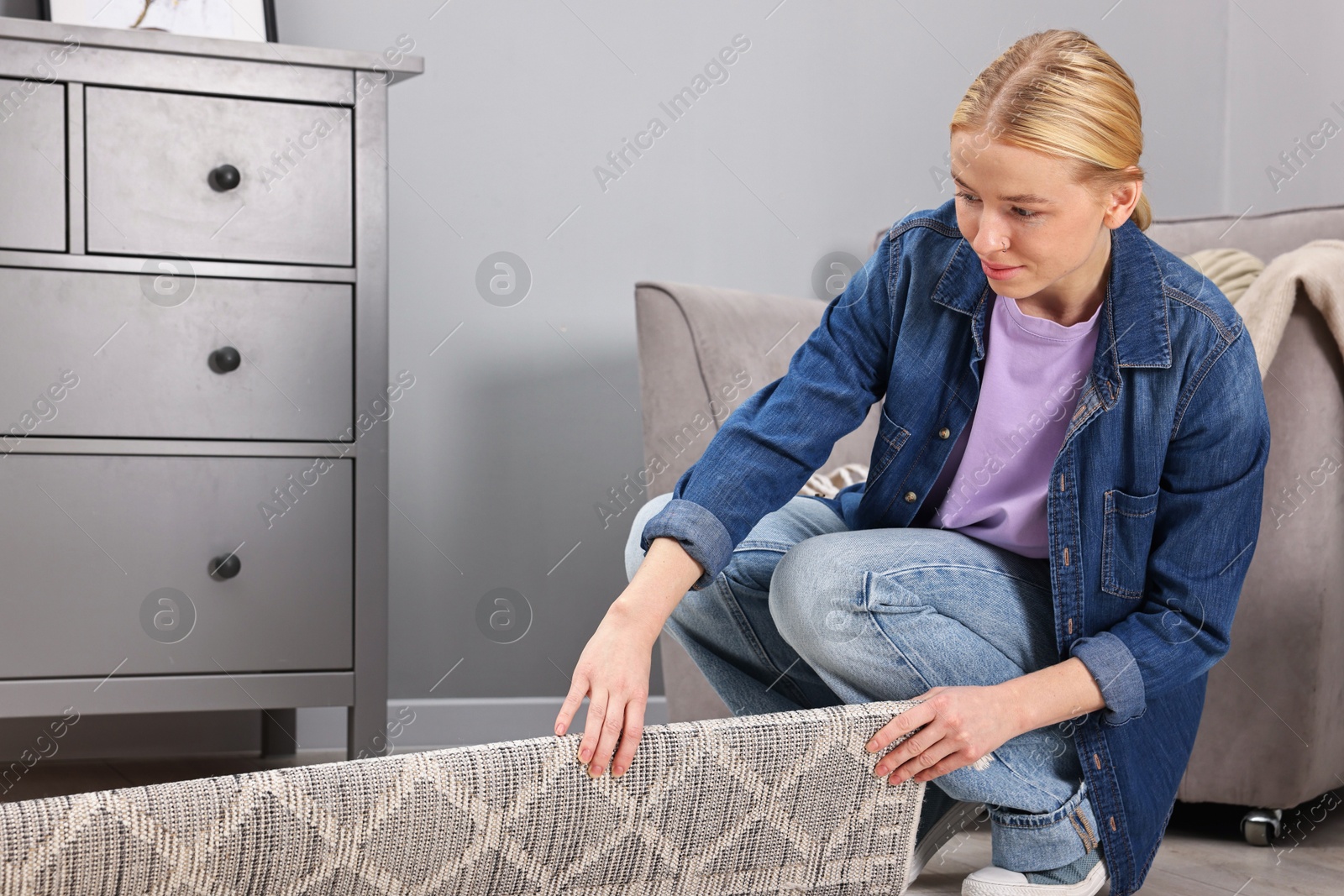 Photo of Female decorator rolling out carpet in room