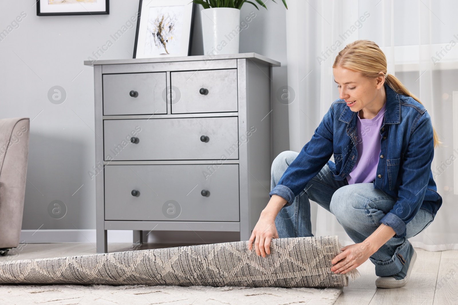 Photo of Happy decorator rolling out carpet in room