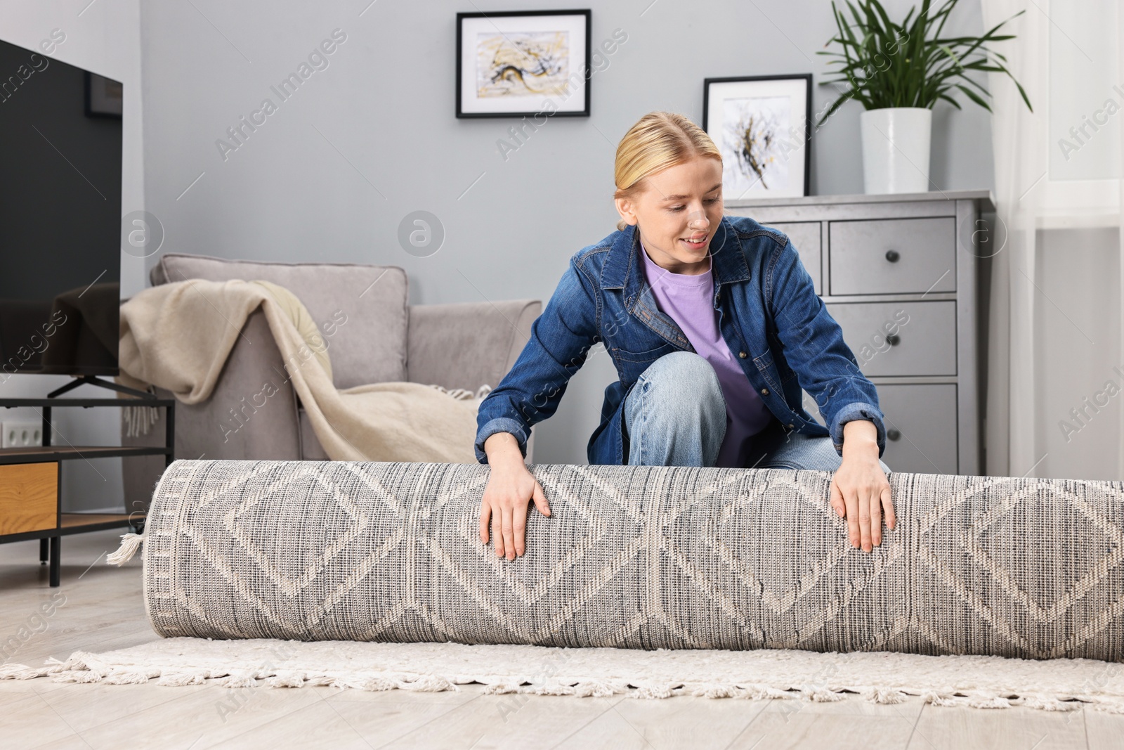 Photo of Happy decorator rolling out carpet in room