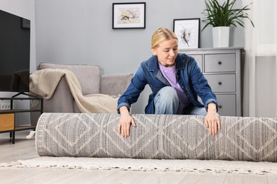 Photo of Happy decorator rolling out carpet in room