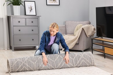 Photo of Female decorator rolling out carpet in room