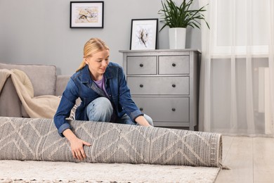 Photo of Happy decorator rolling out carpet in room