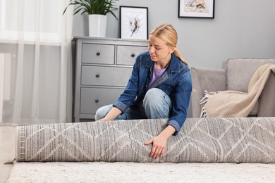 Photo of Happy decorator rolling out carpet in room