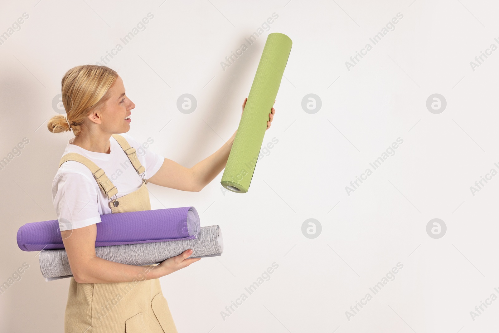 Photo of Smiling worker with rolls of wallpapers indoors, space for text