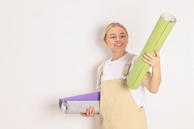 Smiling worker with rolls of wallpapers indoors, space for text