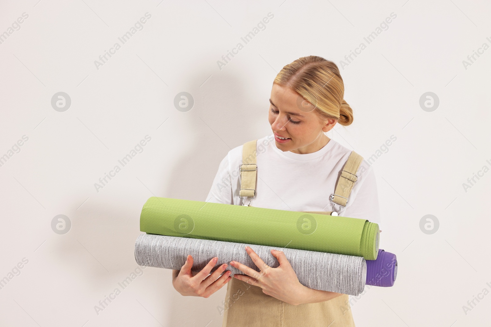 Photo of Smiling worker with rolls of wallpapers indoors