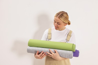 Photo of Smiling worker with rolls of wallpapers indoors