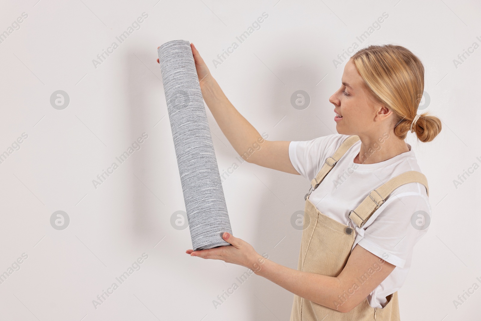 Photo of Smiling worker with roll of grey wallpaper indoors, space for text