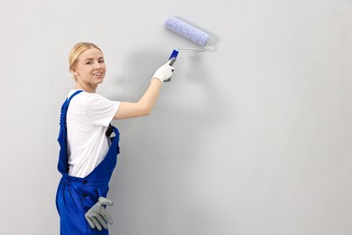 Photo of Smiling worker painting wall with roller indoors. Space for text