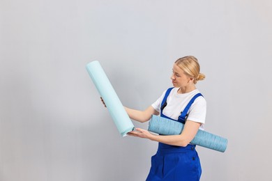 Photo of Female worker with rolls of wallpapers indoors, space for text