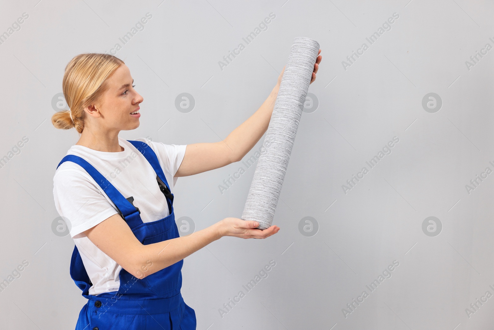 Photo of Smiling worker with roll of wallpaper indoors, space for text