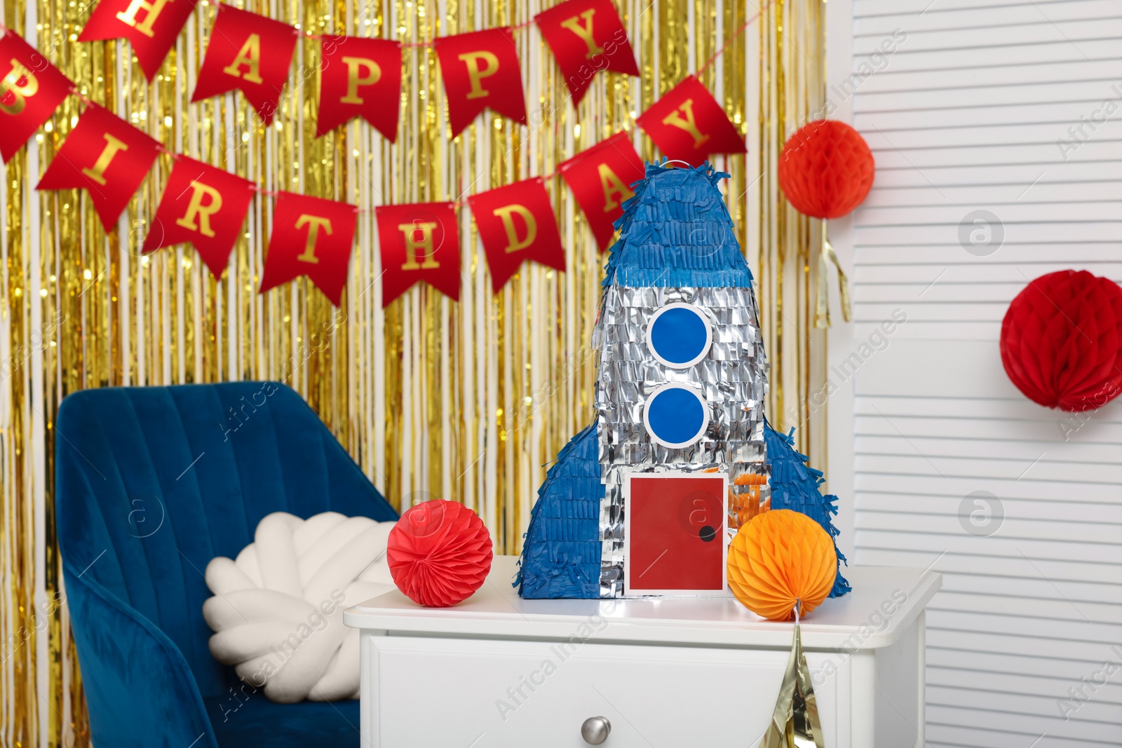 Photo of Bright pinata in shape of rocket and party accessories in festive decorated room