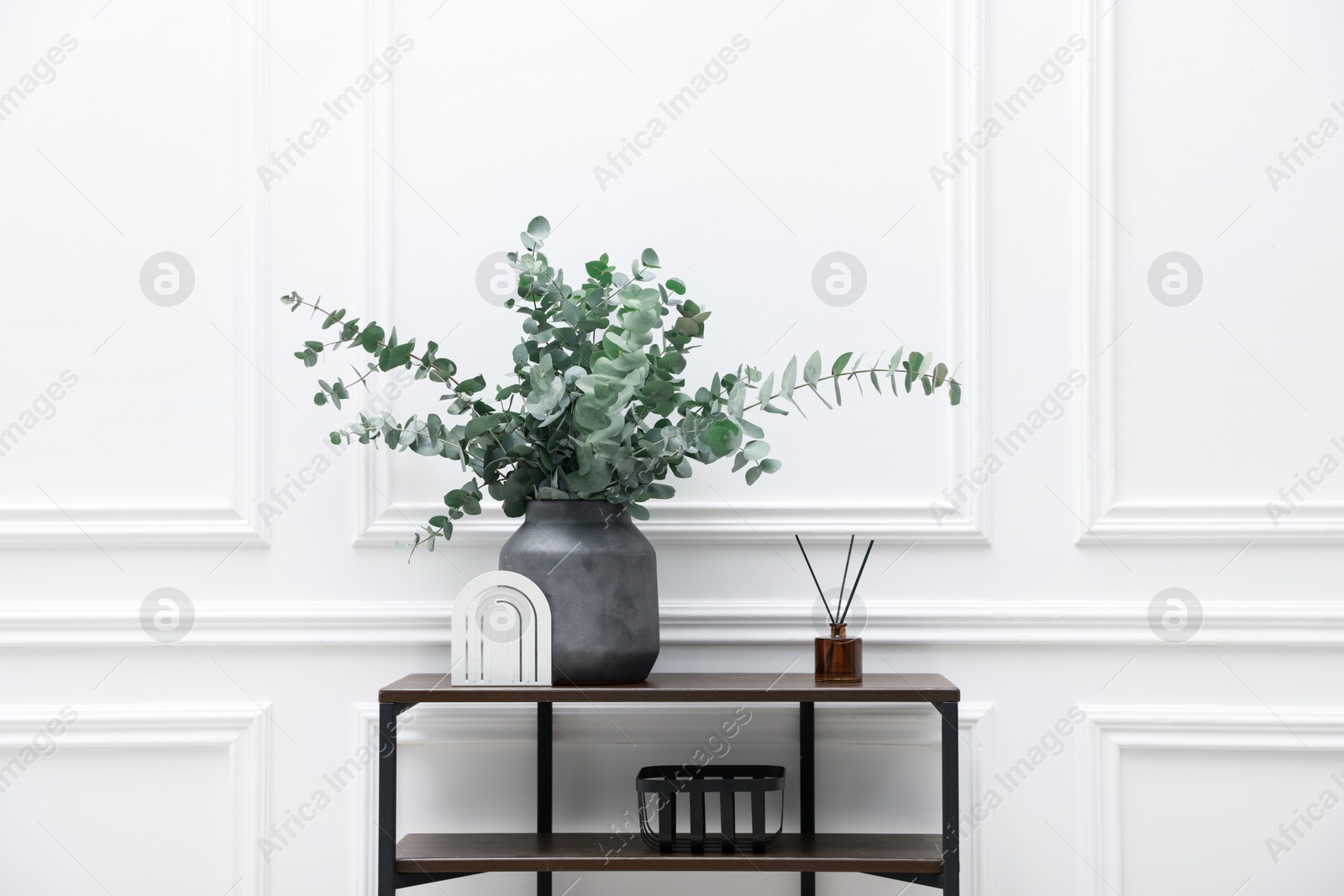 Photo of Console table with decor near white wall in room. Interior design