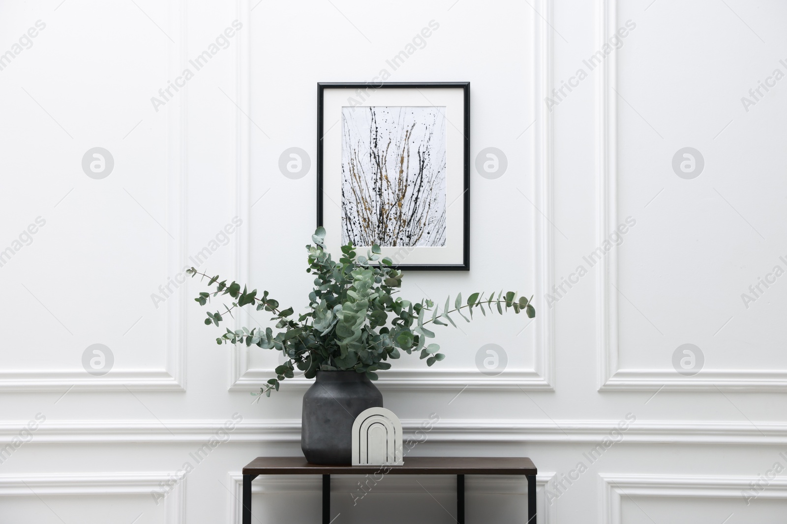 Photo of Console table with decor near white wall in room. Interior design