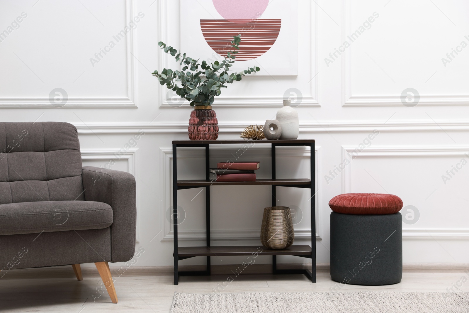 Photo of Console table with decor and armchair near white wall in room. Interior design