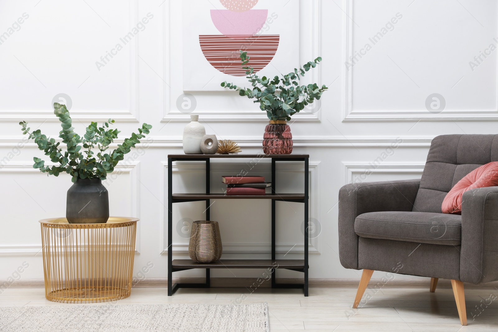 Photo of Console table with decor and armchair near white wall in room. Interior design