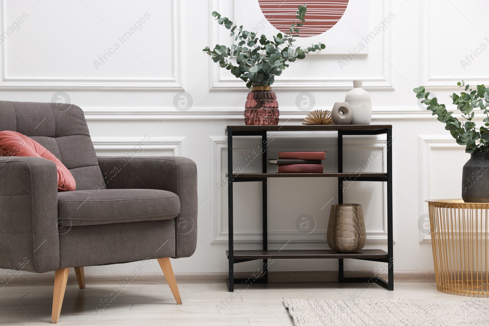 Photo of Console table with decor and armchair near white wall in room. Interior design