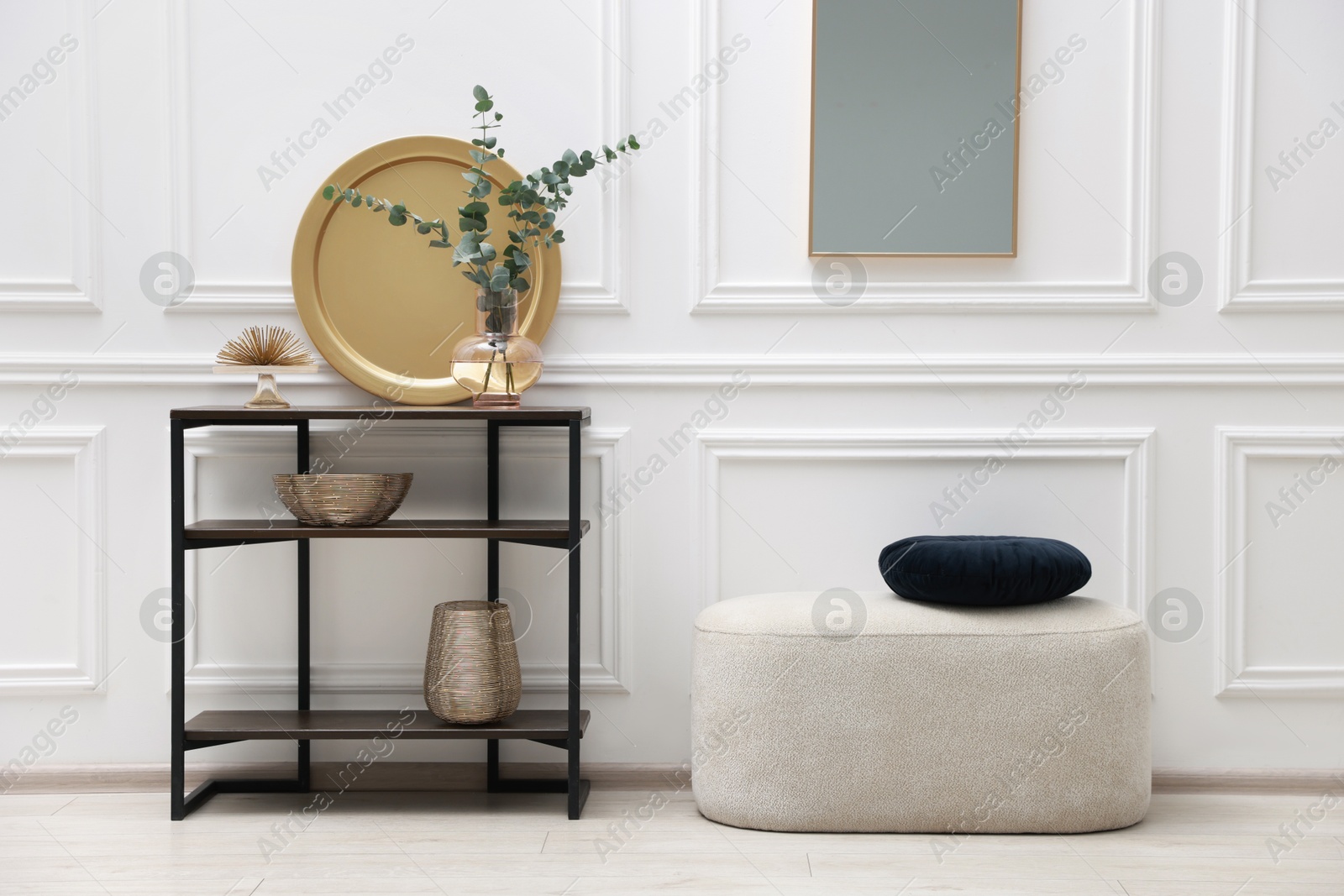 Photo of Console table with decor, pouf and mirror in room. Interior design