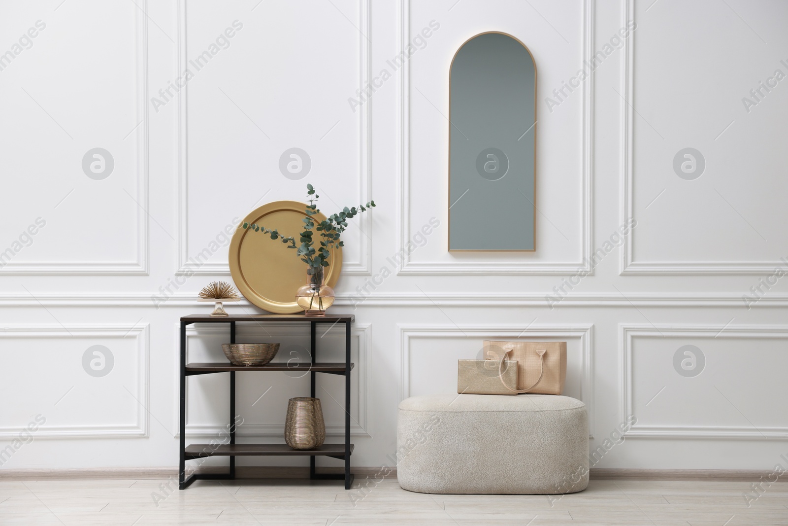 Photo of Console table with decor, pouf and mirror in room. Interior design