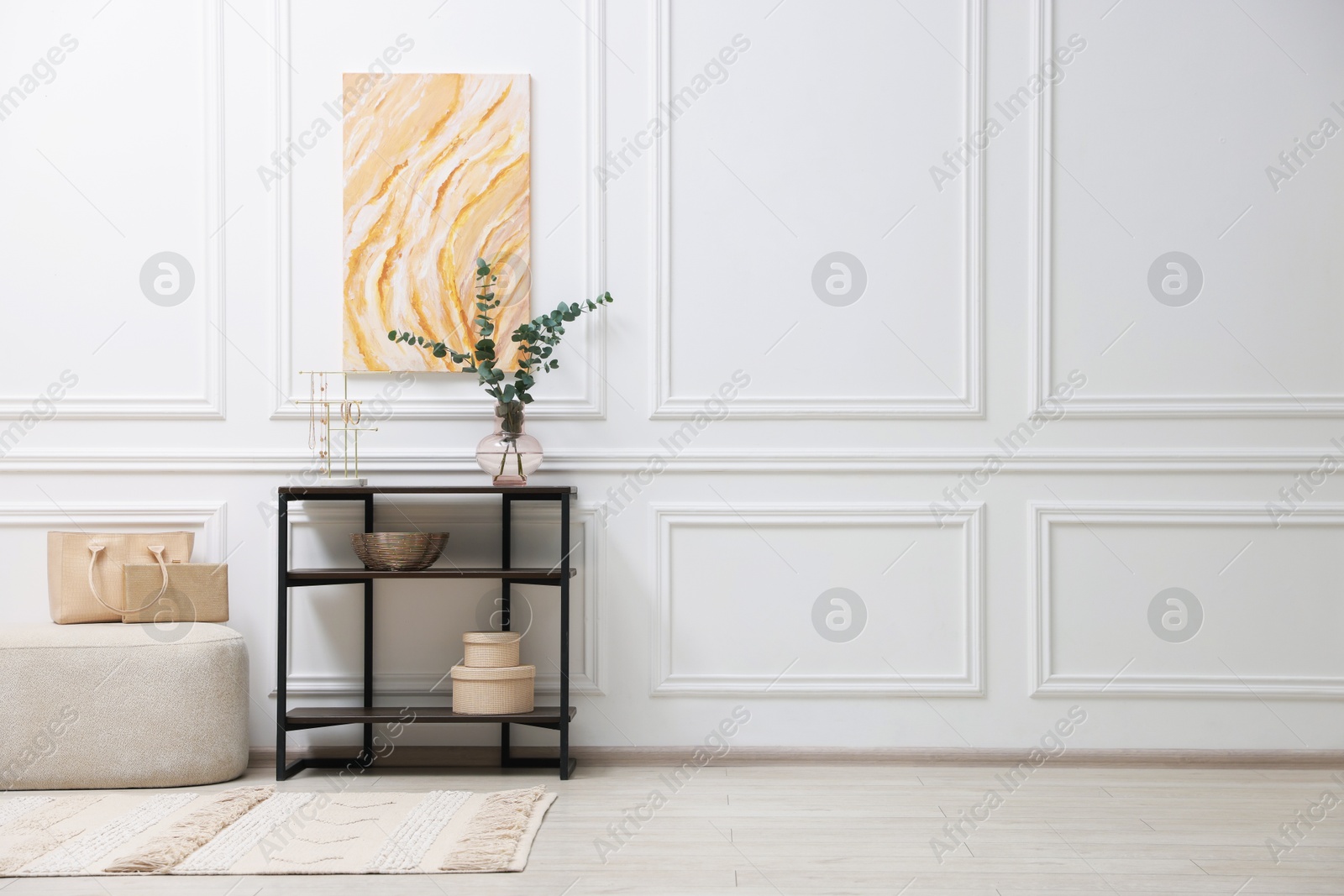 Photo of Console table with decor and pouf near white wall in room, space for text. Interior design