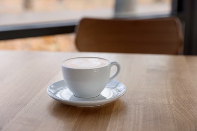 Photo of Cup of aromatic coffee on wooden table in cafe