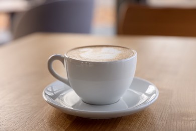 Photo of Cup of aromatic coffee on wooden table in cafe, closeup