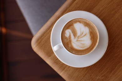 Photo of Cup of aromatic coffee on wooden table in cafe, top view. Space for text