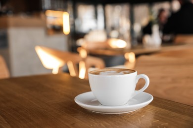 Photo of Cup of aromatic coffee on wooden table in cafe, closeup. Space for text