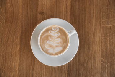 Photo of Cup of aromatic coffee on wooden table, top view