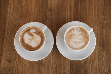 Photo of Cups of aromatic coffee on wooden table, flat lay