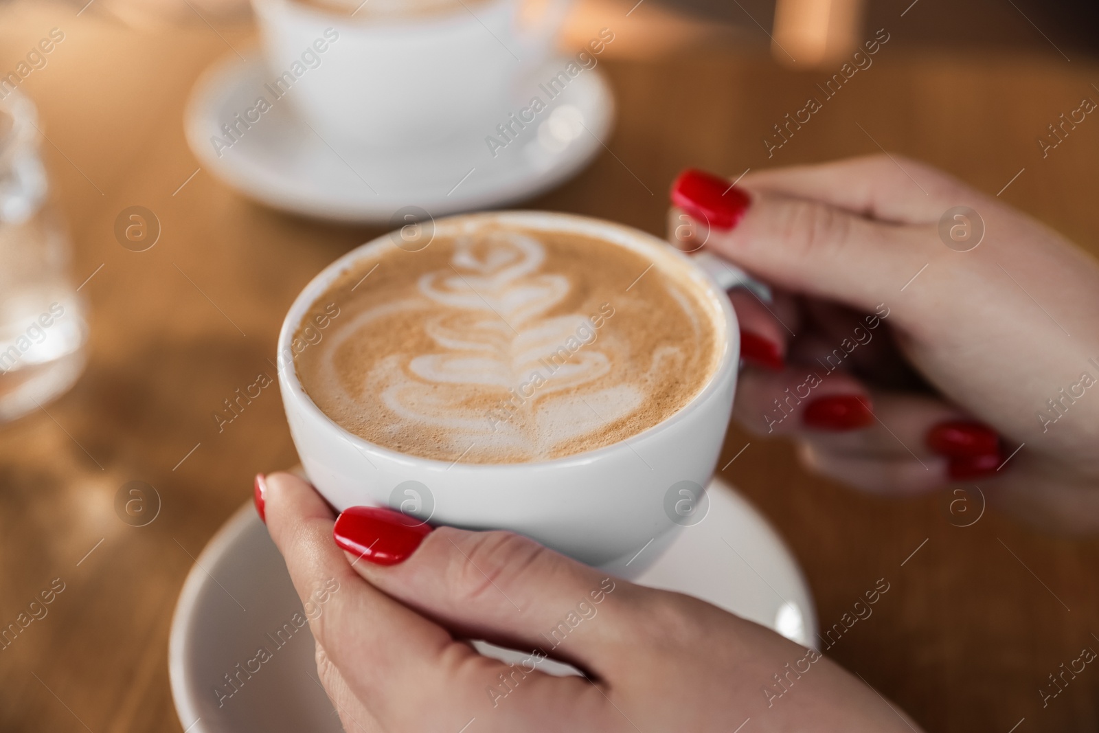 Photo of Woman with cup of aromatic coffee at table in cafe, closeup