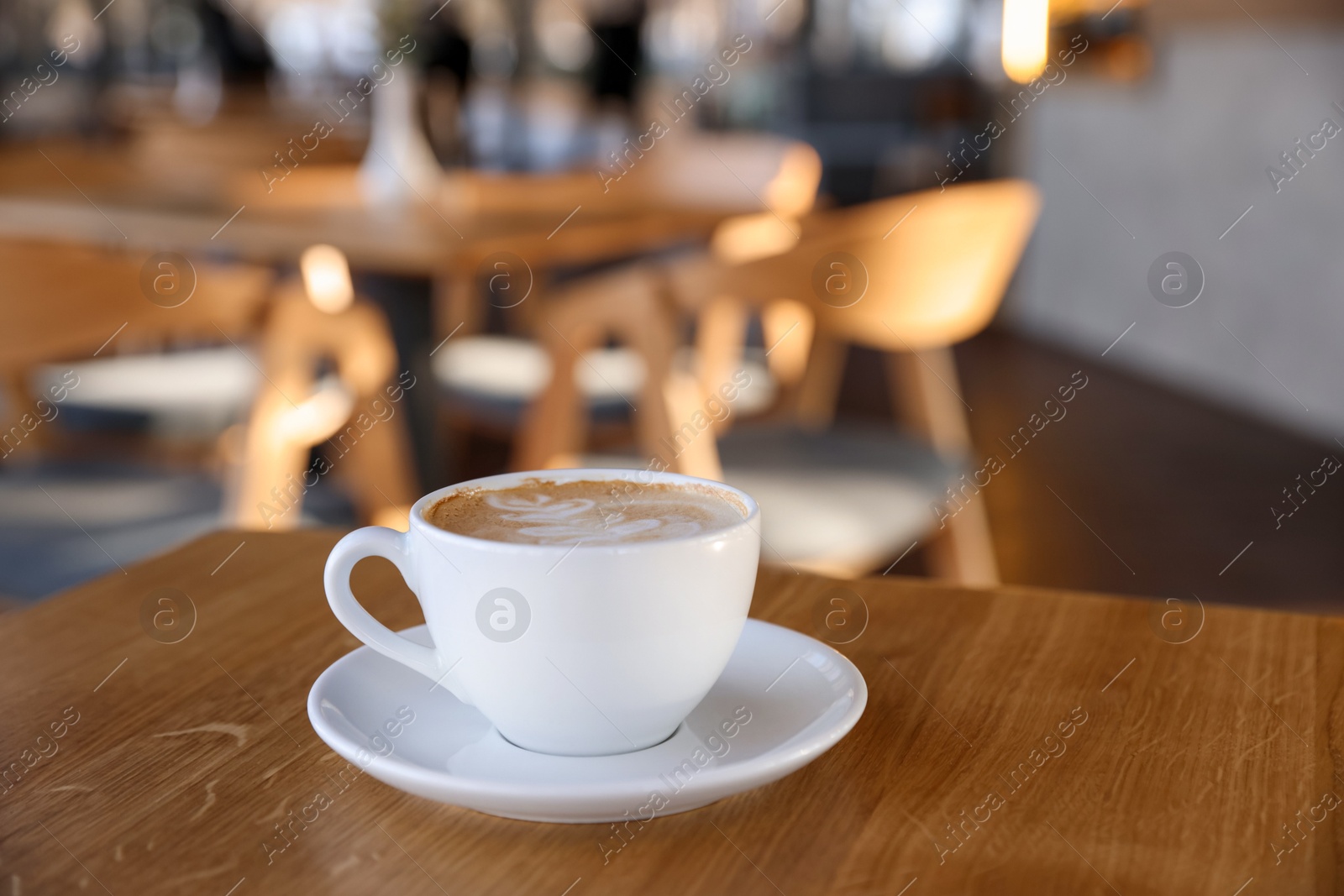 Photo of Cup of aromatic coffee on wooden table in cafe, closeup. Space for text