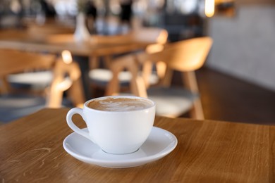 Photo of Cup of aromatic coffee on wooden table in cafe, closeup. Space for text