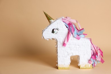 Photo of Unicorn shaped pinata on beige background, space for text